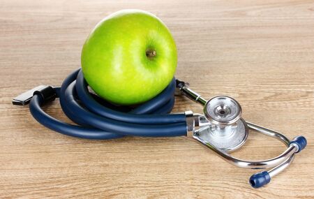 Medical stethoscope and apple on wooden backgroundの写真素材