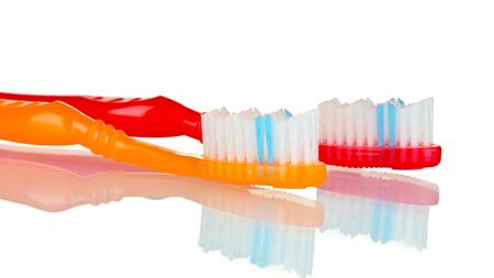 red and orange toothbrushes isolated on whiteの写真素材