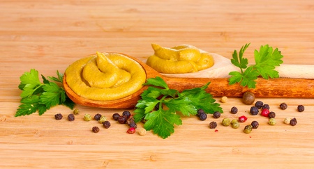 Mustard in wooden spoons, spices and parsley on wooden backgroundの写真素材