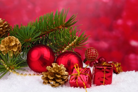 Christmas ball and green tree in the snow on redの写真素材