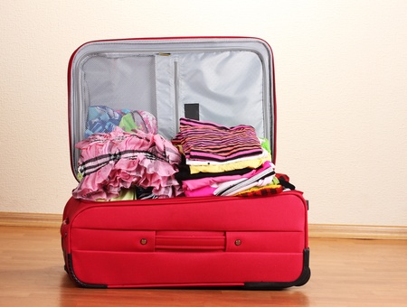 Open red suitcase with clothing in the roomの写真素材
