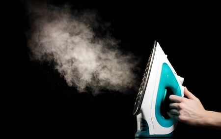 Electric iron with steam on blackの写真素材