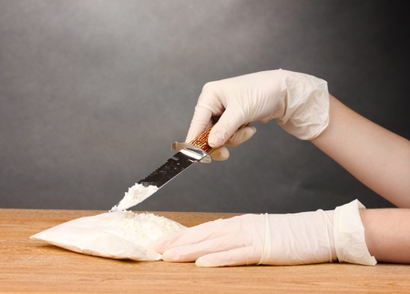 packets of cocaine opening with a knife on wooden table on grey backgroundの写真素材