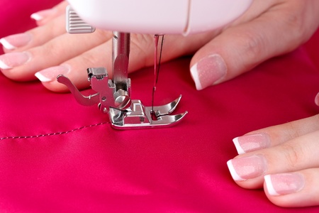 sewing machine, red fabric and women's hands