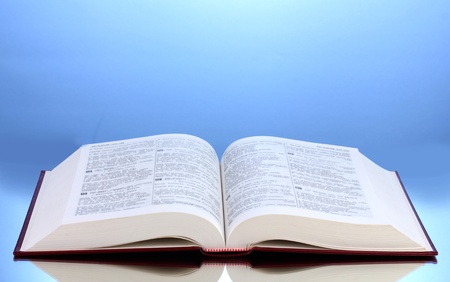 Open book on reflective surface of table on blue backgroundの写真素材