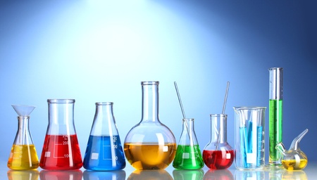Different laboratory glassware with color liquid and with reflection on blue backgroundの写真素材
