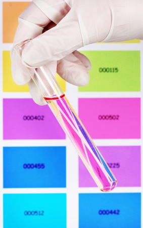 Tube with pink liquid in hand on color samples backgroundの写真素材