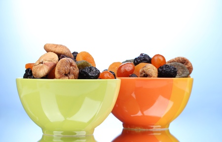 Dried fruits in bright bowls on blue background