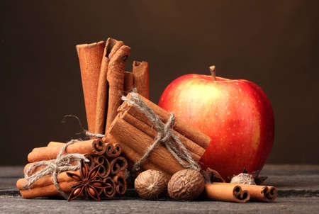 Cinnamon sticks,red apple, nutmeg,and anise on wooden table on brown backgroundの写真素材