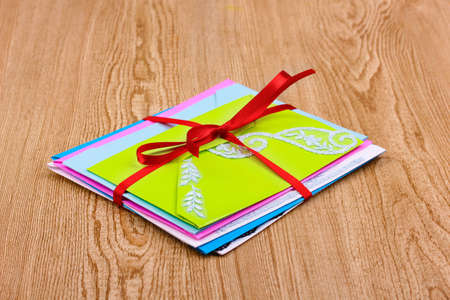 Bunch of color envelopes with ribbon on wooden background