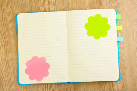 Open note book with stickies on wooden background