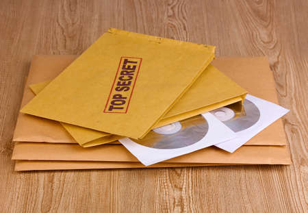 Envelopes with top secret stamp with CD disks on wooden background