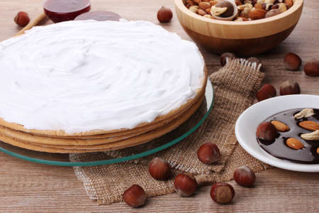 cake on glass stand and nuts on wooden  table