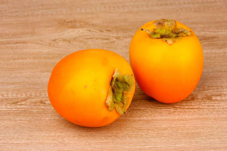 Two appetizing persimmons on wooden backgroundの写真素材
