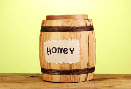 Sweet honey in barrel with drizzler on wooden table on green backgroundの写真素材