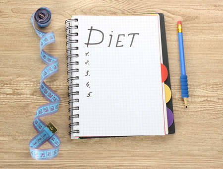 Planning of diet. Notebook measuring tape and pen on wooden tableの写真素材