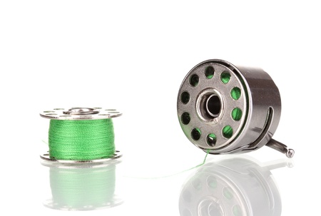 Metal spool of thread and sewing machine shuttle isolated on whiteの写真素材