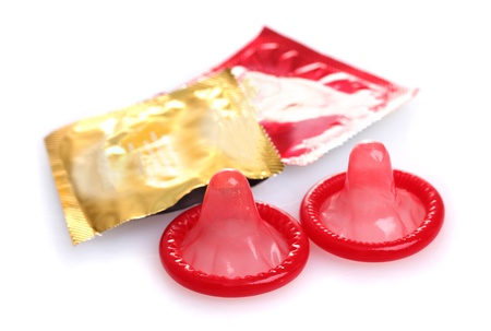 Red condoms with  open packs isolated on whiteの写真素材