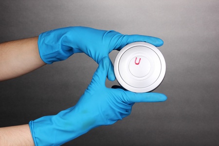 Uranium in hands on grey background