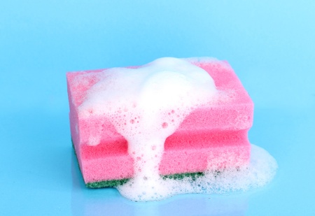 Sponge with foam of dishwashing liquid on blue backgroundの写真素材