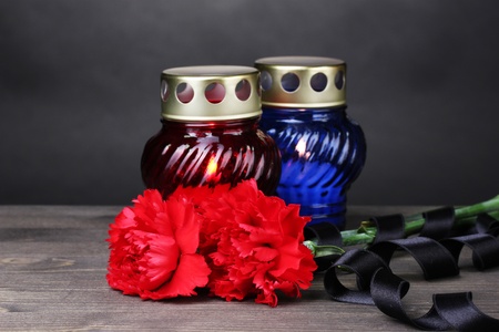 Memory lantern with candles, red carnations and ribbon on wooden table on grey backgroundの写真素材
