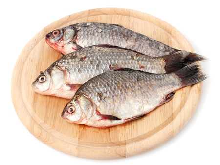 Fresh fishes on wooden cutting board isolated on white