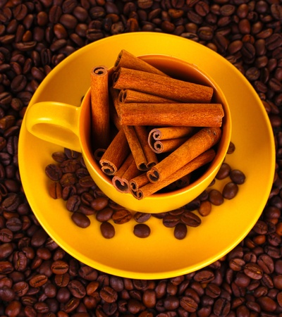 Composition of the yellow cup with coffee beans and cinnamon close-upの写真素材