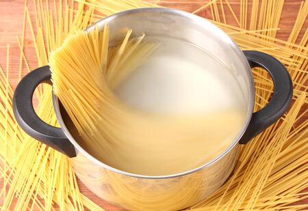 Cook the spagetti in the pan on wooden background close-upの写真素材
