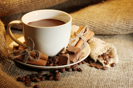 cup of coffee and beans, cinnamon sticks and chocolate on sacking backgroundの写真素材