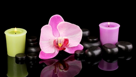 Spa stones with orchid flower and candles isolated on blackの写真素材