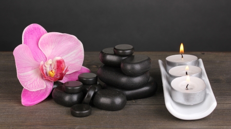 Spa stones with orchid flower and candles on wooden table on grey backgroundの写真素材