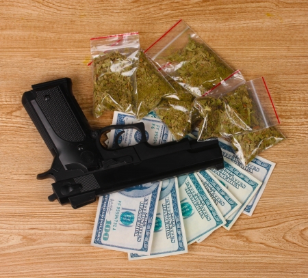 marihuana in packages, dollars and handgun on wooden backgroundの写真素材