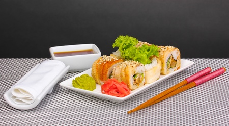Tasty rolls served on white plate with chopsticks on grey mat on grey backgroundの写真素材