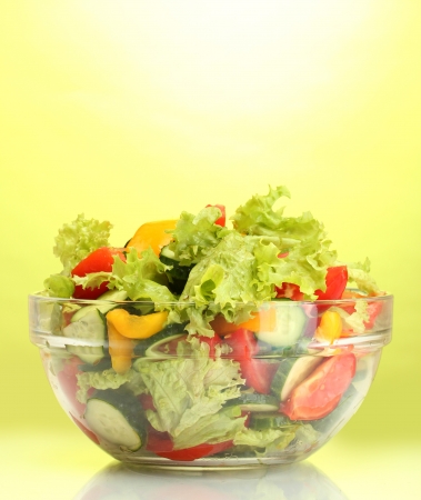fresh vegetable salad in transparent bowl on green backgroundの写真素材