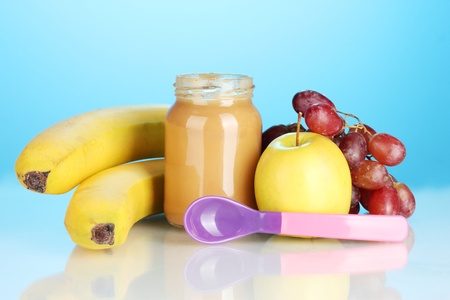 Jar with fruit baby food and spoon on colorful backgroundの写真素材