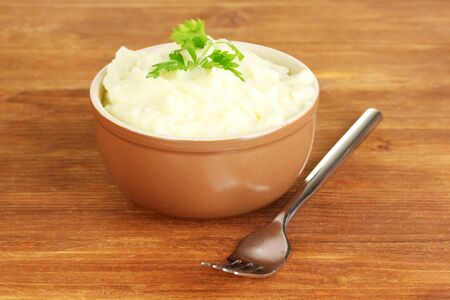 Mashed potato with parsley in the bowl on wooden background close-upの写真素材