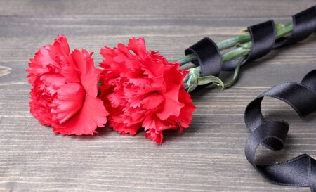 carnations and black ribbon on grey wooden backgroundの写真素材