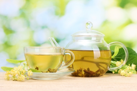 teapot and cup with linden tea  and flowers on wooden table in garden
の写真素材