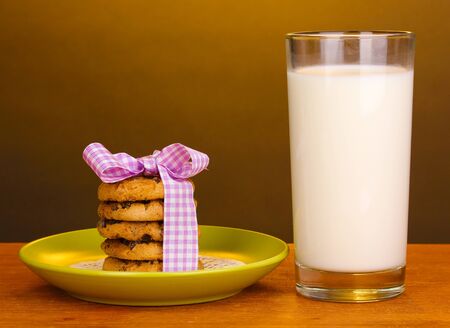 Glass of milk and cookies on wooden table on brown backgroundの写真素材