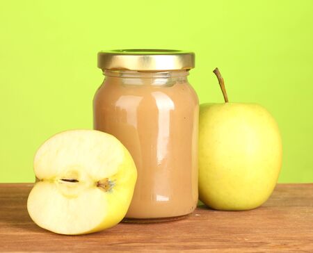 Jar with apple baby food on wooden table on colorful background close-upの写真素材