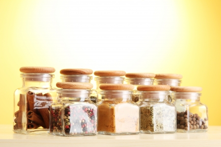 powder spices in glass jars on yellow backgroundの写真素材