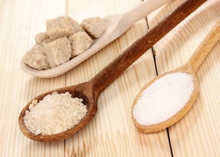 White and brown sugar in spoons on wooden backgroundの写真素材