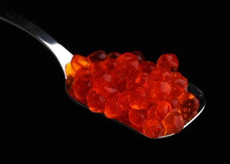 Red caviar in silver spoon isolated on whiteの写真素材