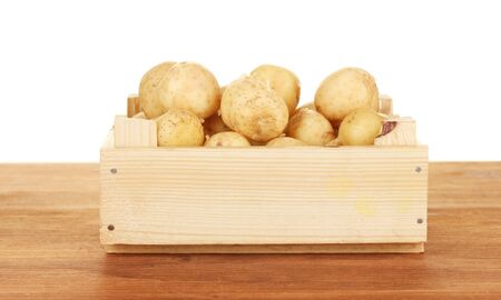 young potatoes in a wooden box on a table on white background close-upの写真素材