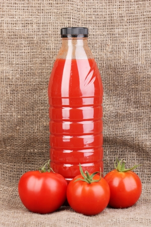 Tomato juice in bottle on sackcloth backgroundの写真素材