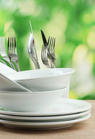 Clean dishes on wooden table on green backgroundの写真素材