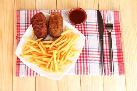 Potatoes fries with burgers on the plate on wooden background close-upの写真素材