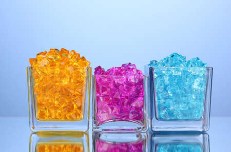 A glasses with colorful decorative stones on blue background close-upの写真素材