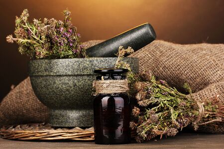 Thyme herb and mortar on wooden table on brown backgroundの写真素材