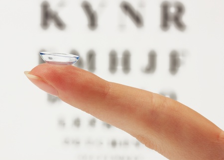 contact lens on finger, on snellen eye chart backgroundの写真素材